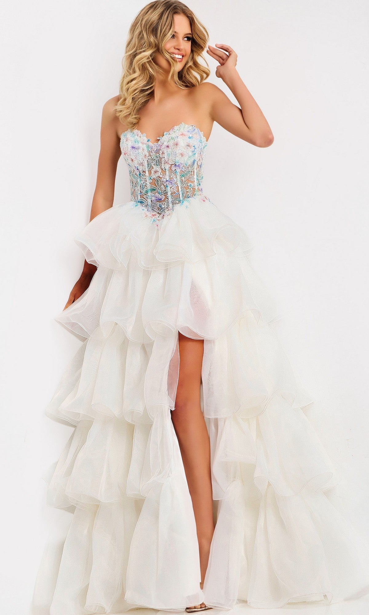 A woman poses in the Jovani 48177 Long Prom Dress, featuring a strapless white gown with a beaded corset bodice, tiered tulle skirt, and high slit against a plain background.
